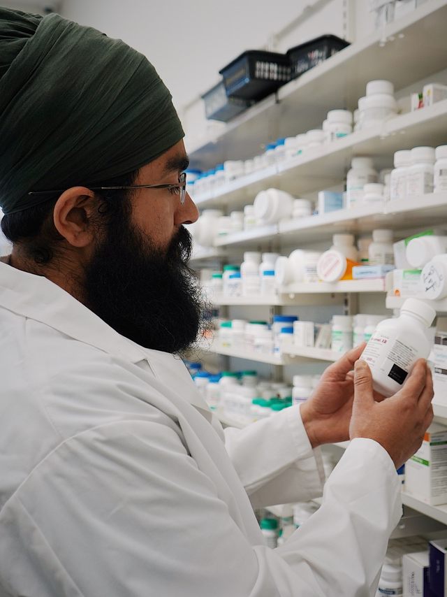 A pharmacist reviewing medication on the shelf